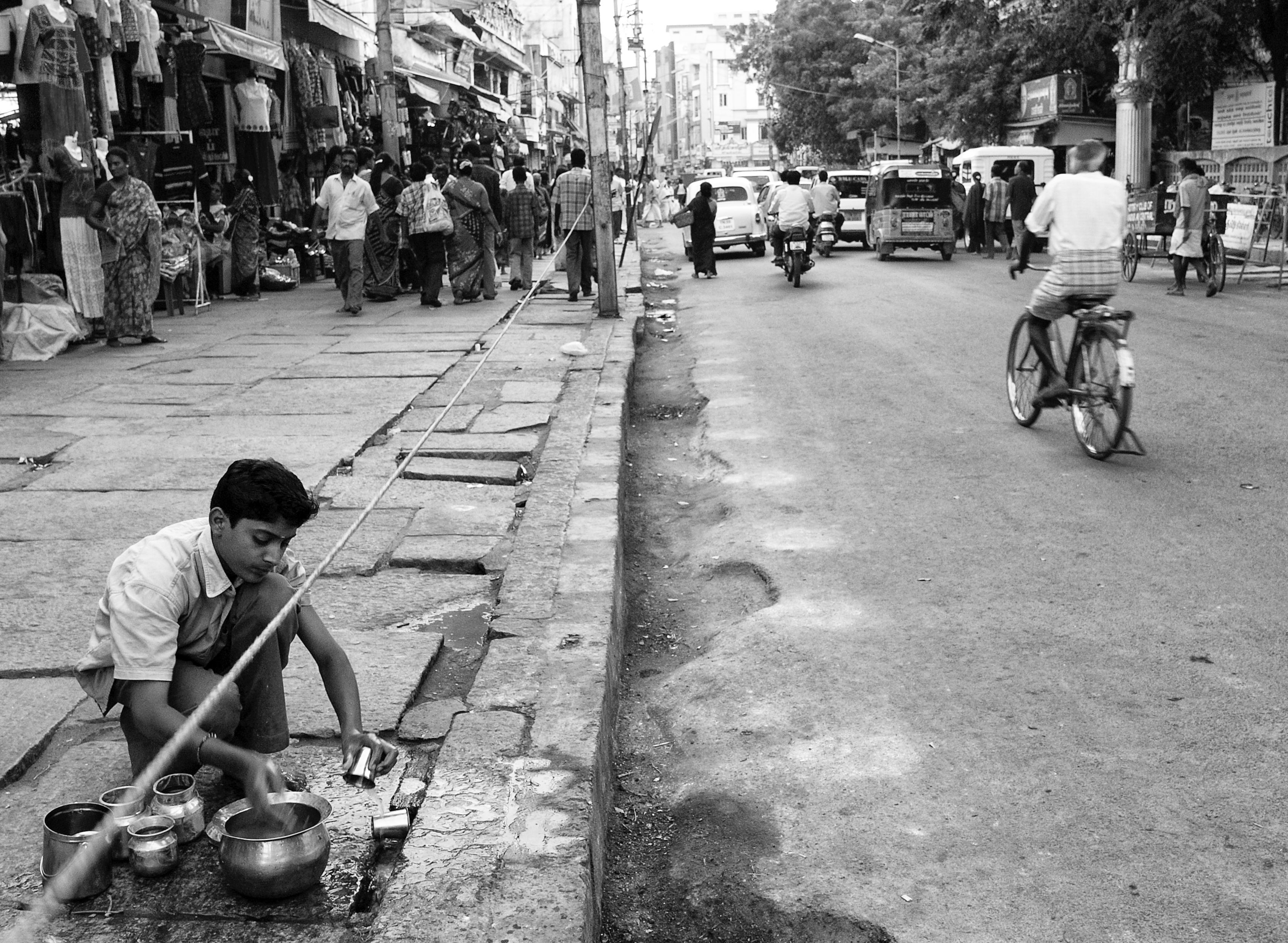 An young boy washing and cleaning the dishes along the road, Madurai, India