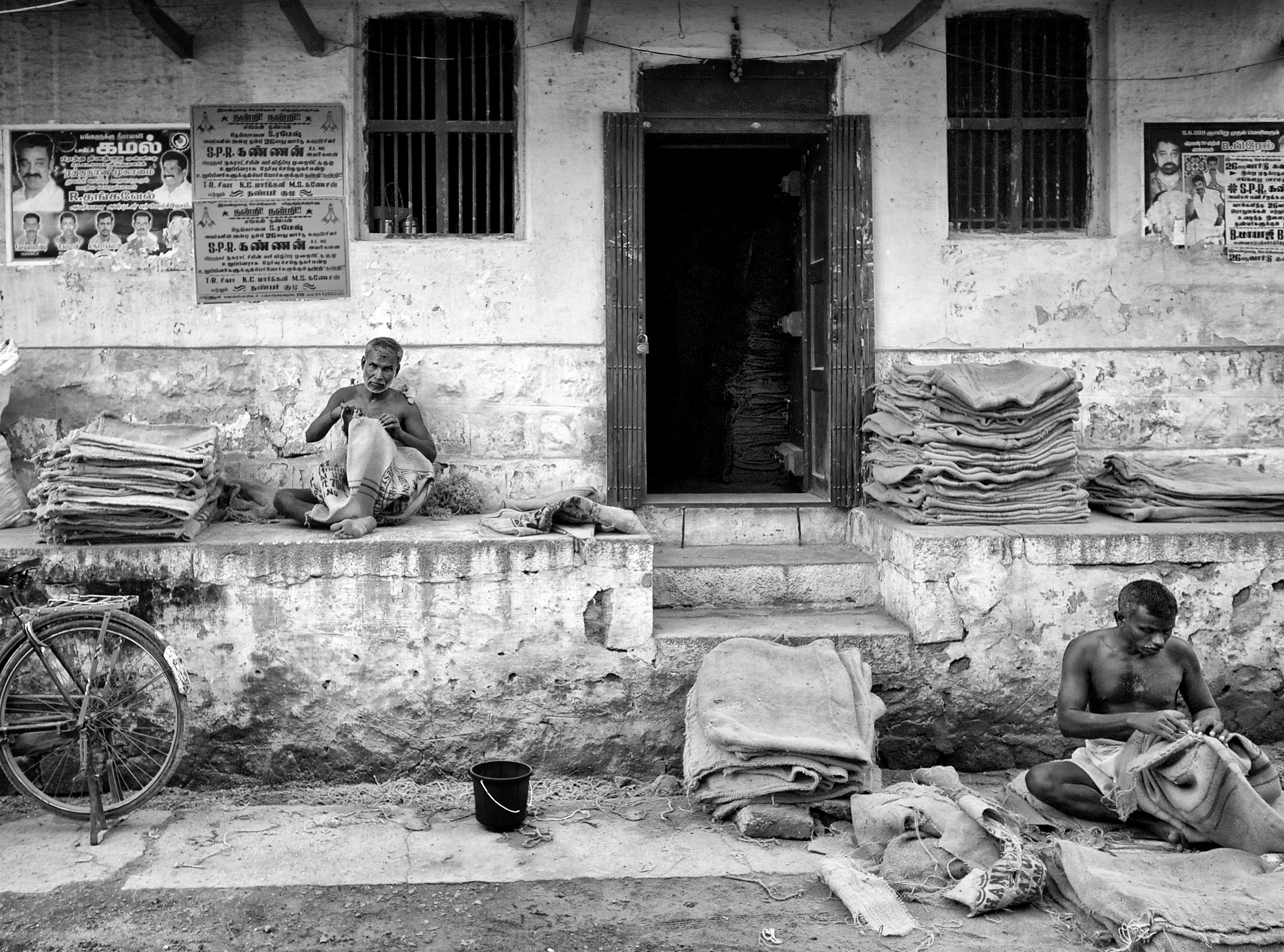 Workers patching up the jute sacks for reuse, in front of a warehouse. Virudhunagar, India
