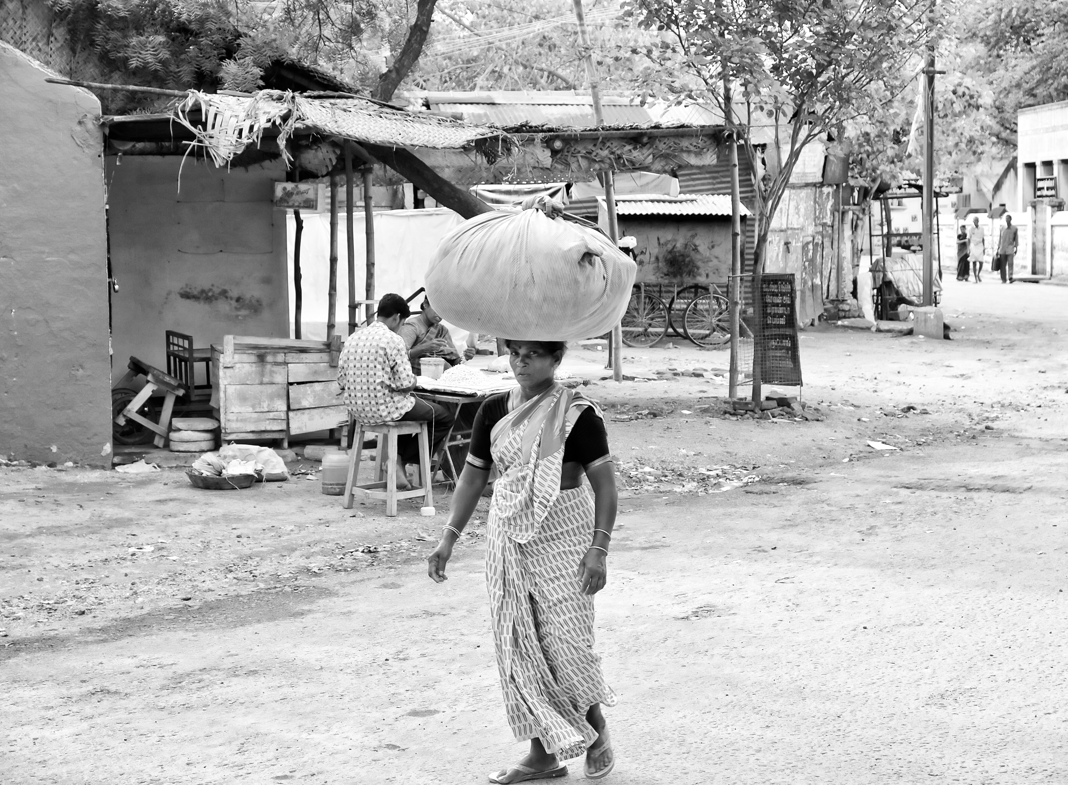 A washerwoman carrying a bundle of laundry to deliver to her customers' homes. Virudhunagar, India