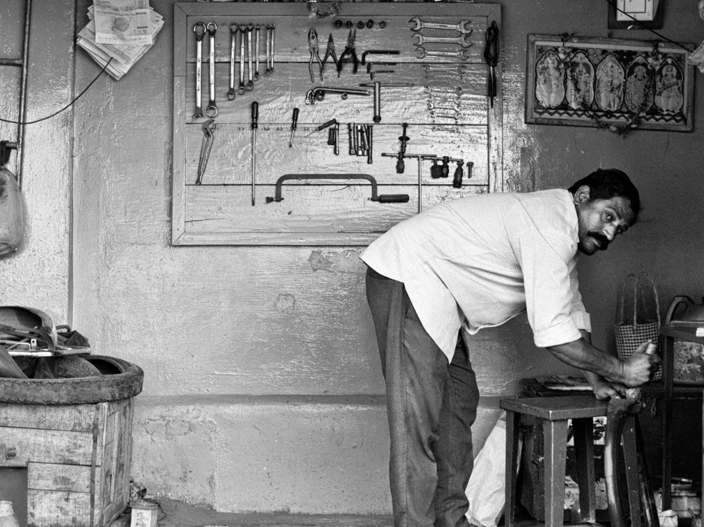 An auto mechanic at work in his workshop by the roadside, Madurai, India