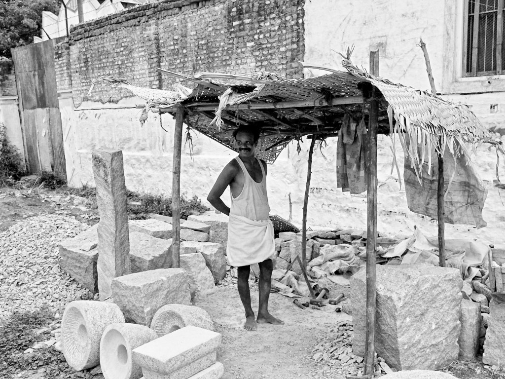 A craftsman who sculpts manual grinders for households from stones, in his roadside workshop. Virudhunagar, India.