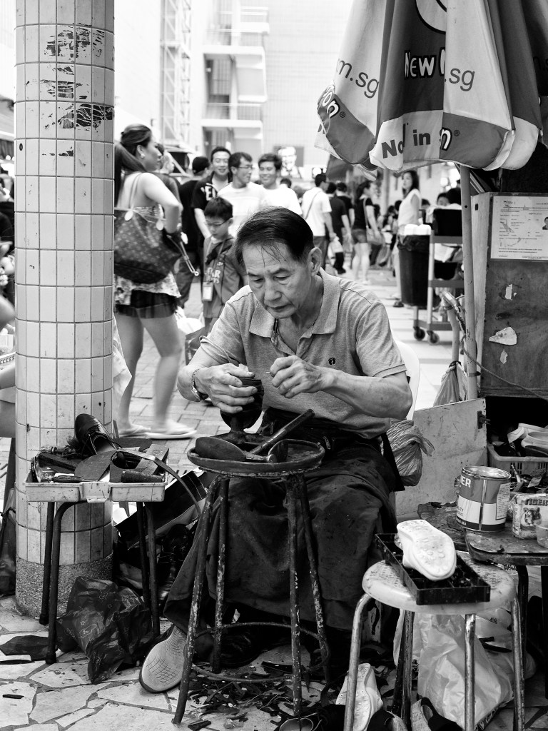 A shoe-repairman at work outside a hawker centre at People's Park Centre, ChinaTown, Singapore