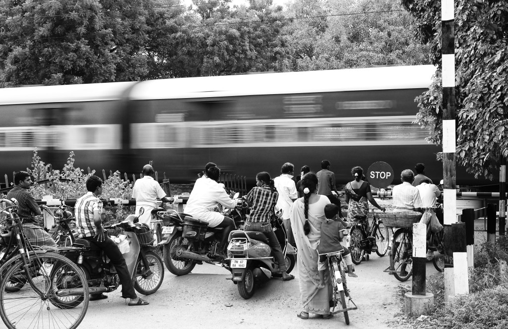People are waiting as the train is passing through the railway crossing. Virudhunagar, India. People are waiting as the train is passing through the railway crossing. Virudhunagar, India.
