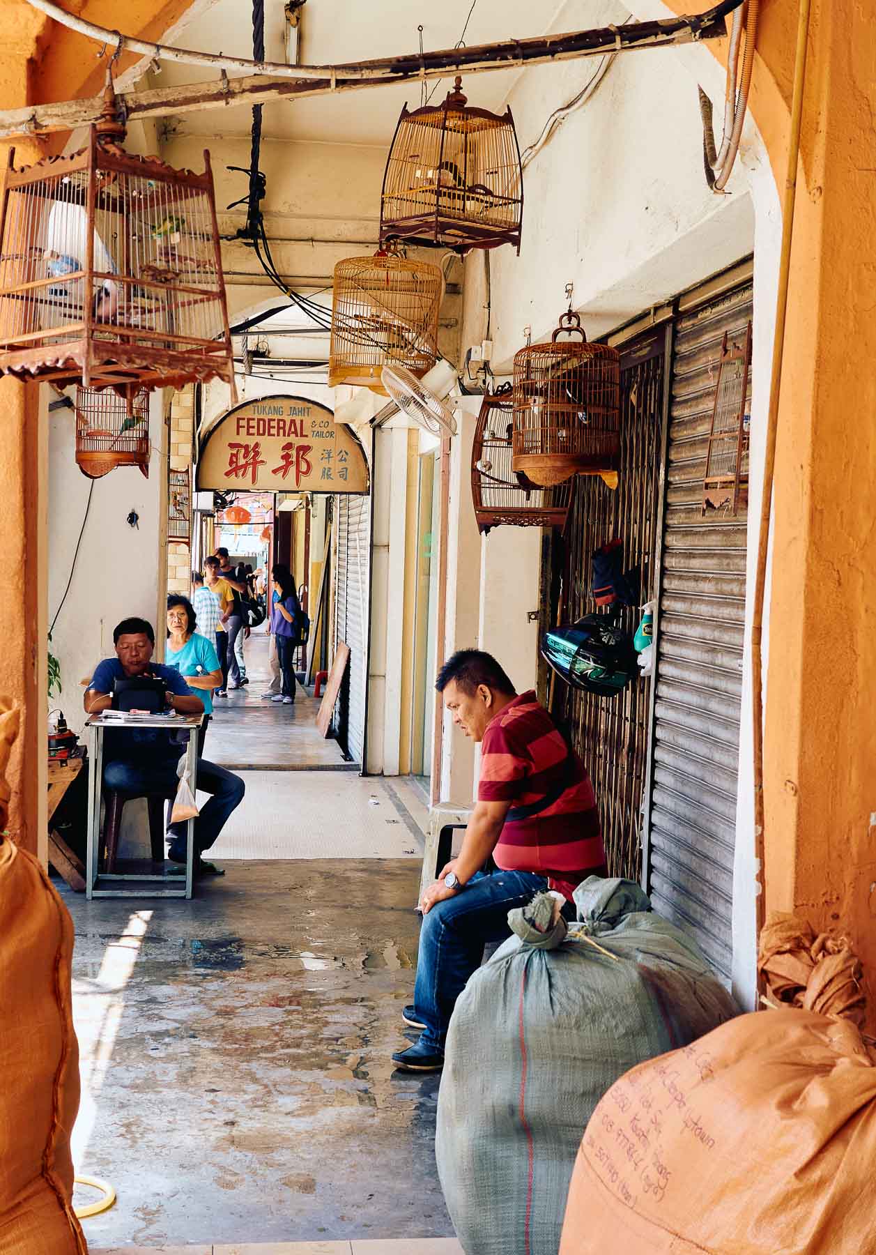 Pet birds seller and other sellers along a shop house corridor at Jalan Petaling, Kuala Lumpur, Malaysia